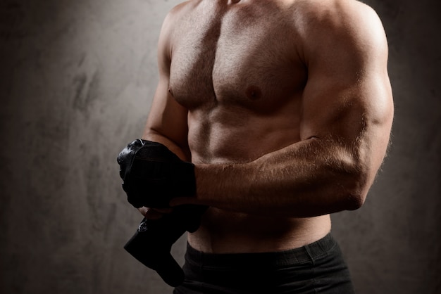 El cuerpo del hombre deportivo sobre la pared oscura.