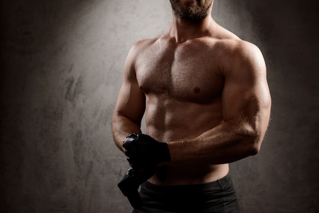 Foto gratuita el cuerpo del hombre deportivo sobre la pared oscura.