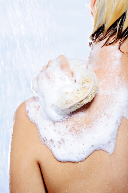 Cuidado corporal por mujer tomando ducha aislado en blanco