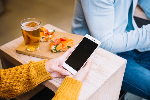 Cultivar las manos femeninas sosteniendo el teléfono inteligente