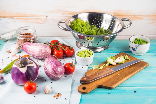 Cultive el ingrediente vegetal fresco y el utensilio de la cocina en la tabla de madera azul