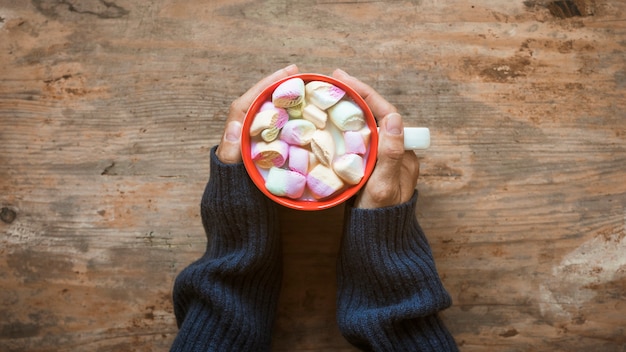 Cultive las manos calentándose cerca del chocolate caliente