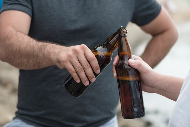 Cultivo hombres tintineo de botellas en la playa