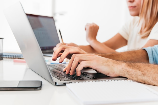 Foto gratuita cultivo de manos escribiendo en la computadora portátil en el lugar de trabajo