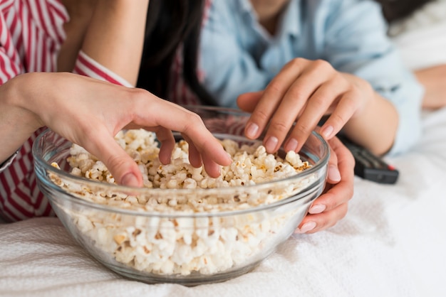 Cultivo de manos de mujeres comiendo palomitas de maíz.