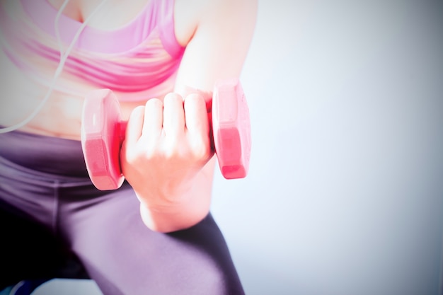 Culturismo. Mujer de ajuste fuerte en sujetador de deporte de color rosa ejercicio con pesas rojas. Copiar espacio