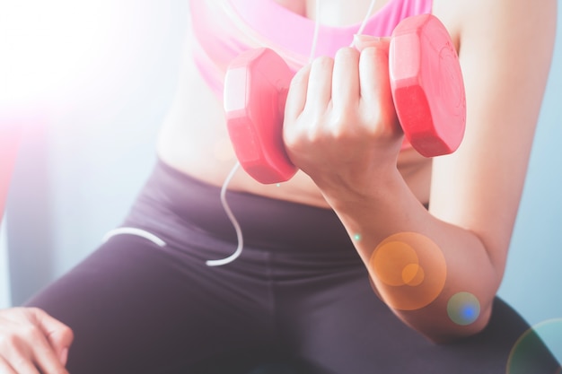 Culturismo. Mujer de ajuste fuerte en sujetador de deporte de color rosa ejercicio con pesas rojas.