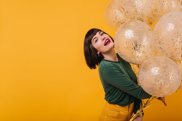 Cumpleañera de moda posando con expresión de la cara interesada. mujer elegante aislada con globos de helio brillo.