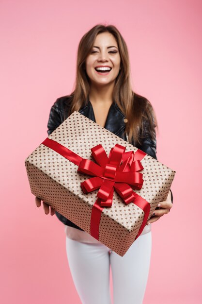 Cumpleañera que muestra su gran caja de regalo con lazo rojo