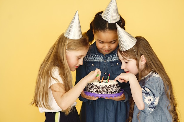 Cumpleaños de niños pequeños aislado en la pared amarilla. niños sosteniendo pastel.