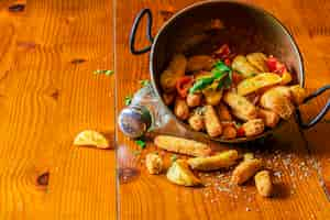 Foto gratuita cuñas de papa frita derramada del utensilio de cobre