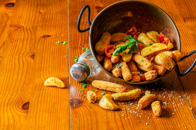 Cuñas de papa frita derramada del utensilio de cobre