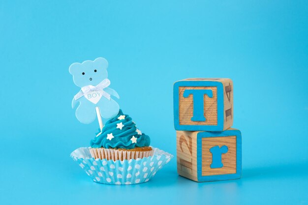 Cupcake azul para baby shower sobre fondo azul.