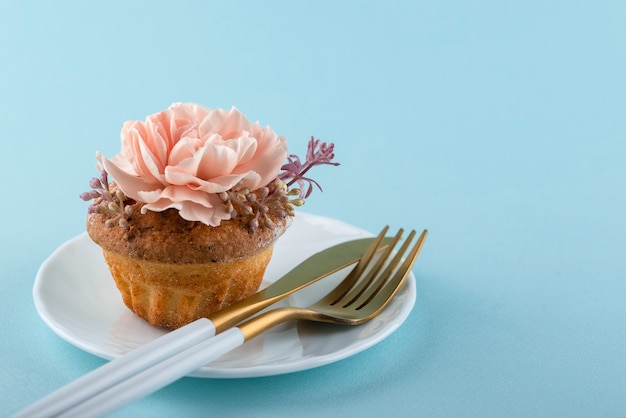 Cupcake con flor y fondo azul ángulo alto