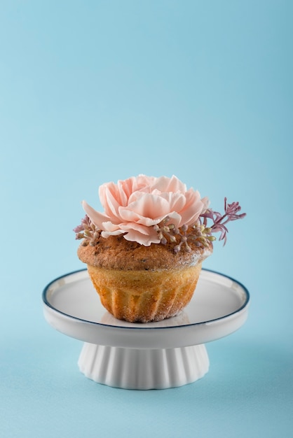 Foto gratuita cupcake con flor y fondo azul.