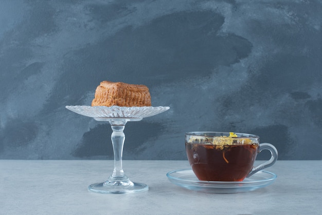 Cupcake en placa de vidrio con té de hierbas caliente sobre fondo oscuro. Foto de alta calidad