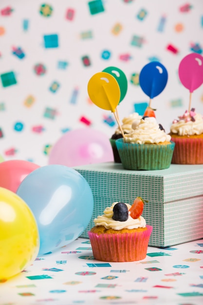 Cupcakes con adornos de globos de papel en caja