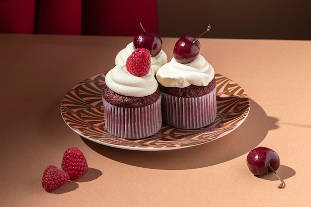 Foto gratuita cupcakes de alto ángulo con cereza y frambuesa