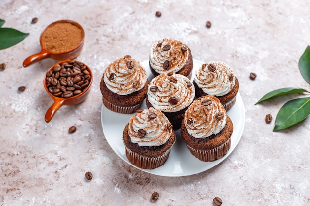 Cupcakes de café decorados con crema batida y granos de café.