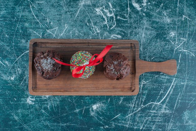 Cupcakes de chocolate y una piruleta recubierta de caramelo sobre una placa sobre fondo azul. Foto de alta calidad