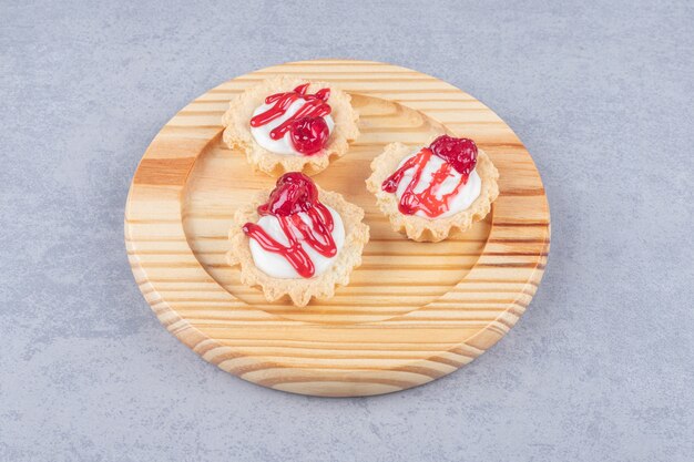 Cupcakes con cobertura de sirope de fresa en una bandeja de madera sobre mármol