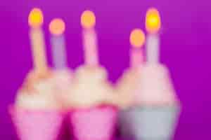 Foto gratuita cupcakes de cumpleaños borrosos con velas encendidas