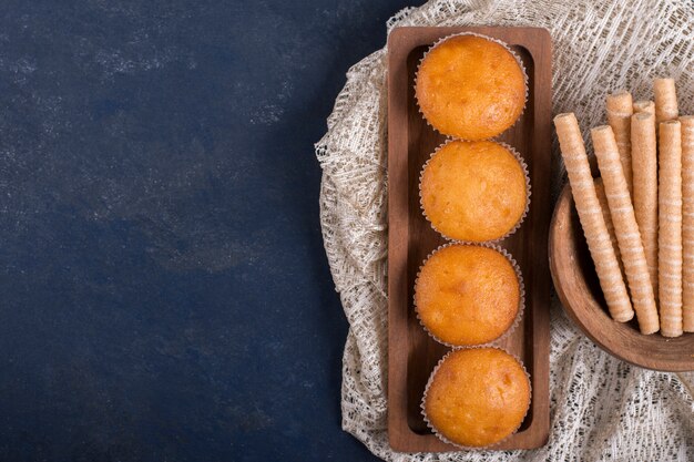 Cupcakes y palitos de gofres en una bandeja de madera, vista superior