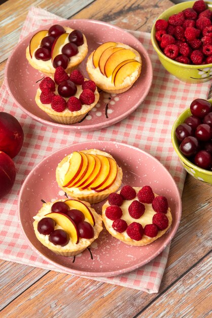 Cupcakes de vainilla con frutos rojos de verano en los platos rosas