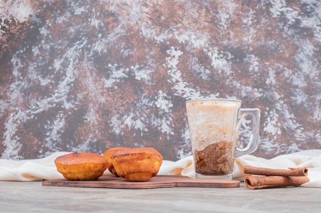 Cupcakes con vaso de galletas y canela sobre tabla de madera.