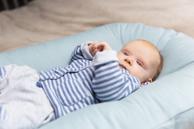 Curioso bebé pensativo pelirrojo con ropa azul y gris