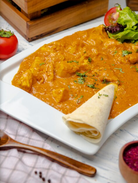 Curry indio con pechuga de pollo y salsa de tomate servido con lavash.