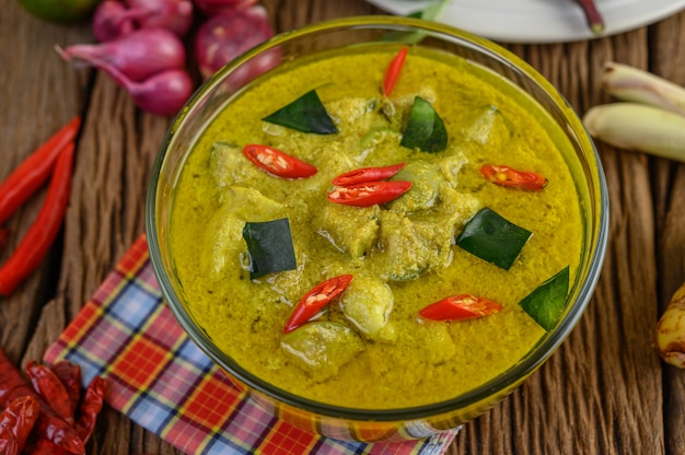 Curry verde en un tazón con lima, cebolla roja, hierba de limón, ajo y hojas de lima kaffir