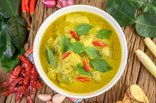 Curry verde en un tazón con lima, cebolla roja, hierba de limón, ajo y hojas de lima kaffir