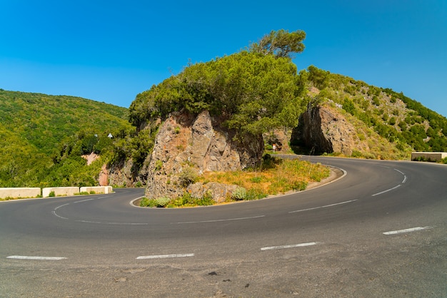 Curva sinuosa carretera escénica en la cordillera de Anaga anainst cielo azul brillante Tenerife, España