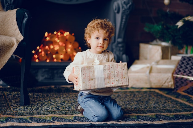 Cutte little boy en casa cerca de decoraciones navideñas