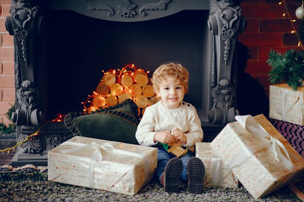 Cutte little boy en casa cerca de decoraciones navideñas