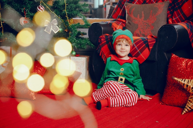 Cutte little boy en casa cerca de decoraciones navideñas