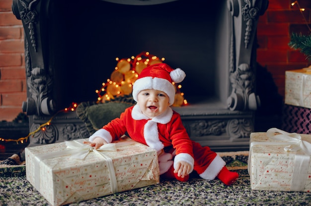 Cutte little boy en casa cerca de decoraciones navideñas