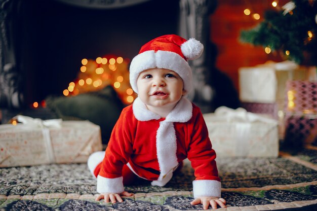 Cutte little boy en casa cerca de decoraciones navideñas