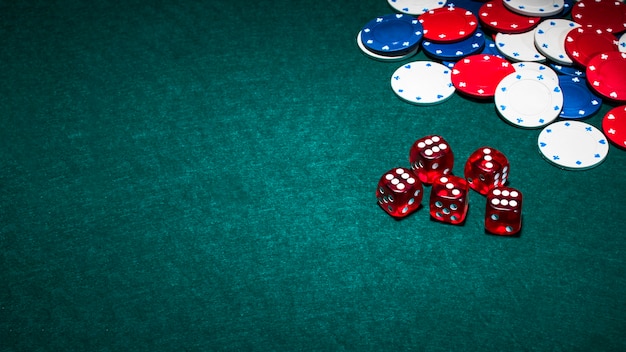 Dados rojos brillantes y fichas de casino sobre fondo verde de póquer