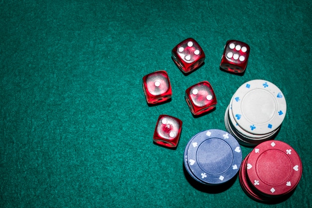 Dados rojos y fichas de casino se apilan en la mesa de póquer verde