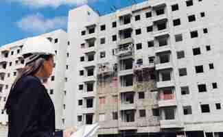 Foto gratuita dama afroamericana en casco de seguridad con papeles cerca del edificio en construcción