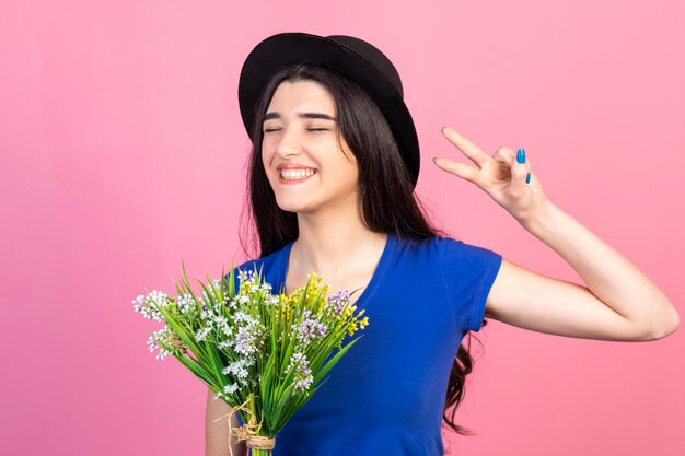 La dama alegre hace un gesto de una pieza y sonríe con un fondo rosa