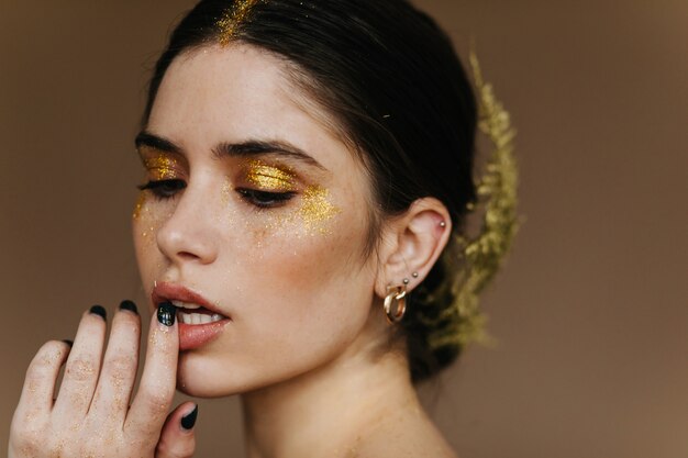 Dama blanca con maquillaje dorado. Impresionante joven preparándose para la fiesta.