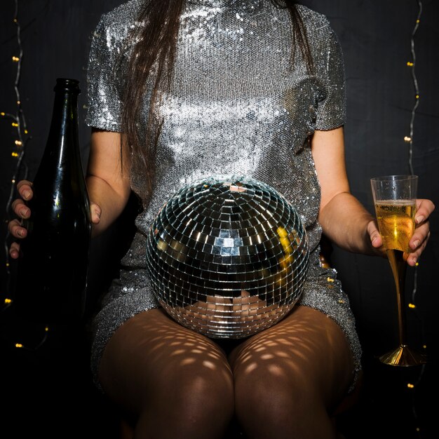 Dama con botella de champagne, copa y bola de discoteca.