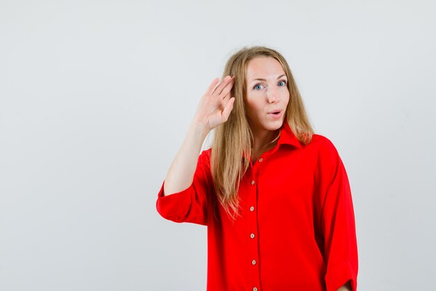 Dama de camisa roja mostrando gesto de saludo y mirando confiado,