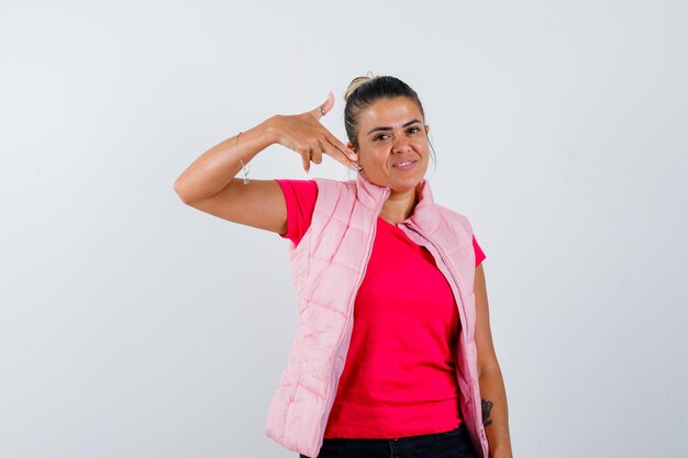 Dama en camiseta, chaleco apuntando a sí misma y luciendo orgullosa