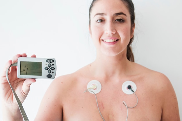 Dama con electrodos sosteniendo monitor con cardiograma