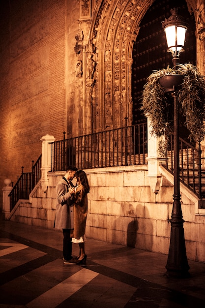 Dama elegante abrazando y tomados de la mano con chico joven en la calle