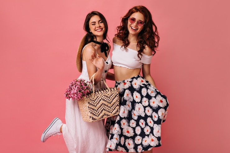 Foto gratuito una dama feliz con una falda elegante y un navegante posando en la pared rosa